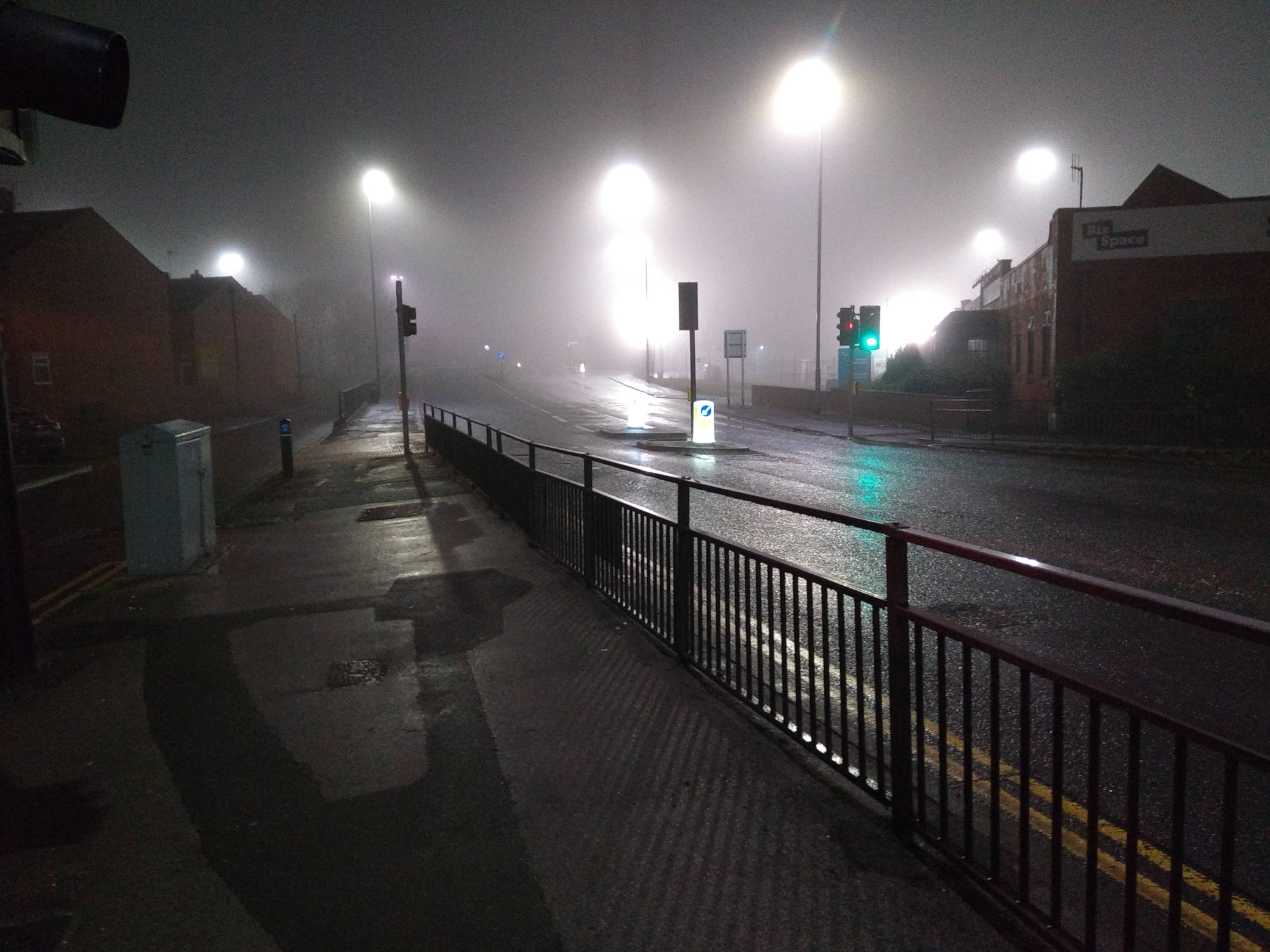 
    Looking along a completely empty major street at night. The street lights are over exposed creating
    big glowing blobs of light. The street fades into the mist in the distance.