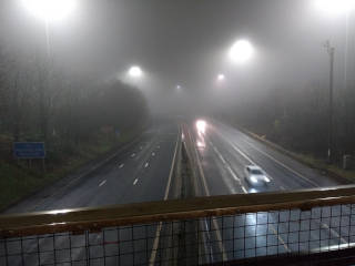 
      A shot from a bridge over a motorway shows the motorway also fading into mist. You can't see far along it.
      There are only two cars visible in this shot coming towards us. The other lane is completely empty.