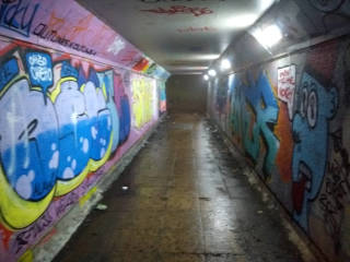 
      Looking down a short tunnel under a road. It's brightly lit and the walls are covered in colourful
      graffiti, but the end of the tunnel is just a dim rectangle.